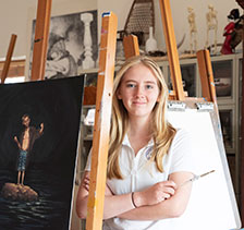 Student by painting. Link to Gifts That Protect Your Assets.
